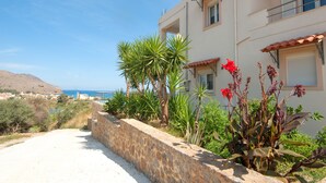 A coastal building with a stone retaining wall, a balcony, and a view of the sea. - Villa Balos with fantastic sea view (Chania)