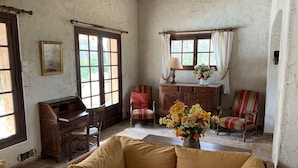 A cozy room with a wooden desk, a cushioned sofa, a chair, and a cabinet with a vase of flowers. - Villa with a 12.5 metre swimming-pool, not far from the sea (Puget-sur-Argens)