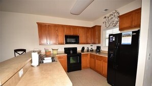 Una cocina con armarios de madera, un refrigerador negro, un microondas y una estufa.