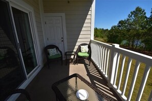 Enjoy a peaceful retreat with a balcony featuring a glass table, two comfortable chairs, and a serene view of the surrounding landscape.