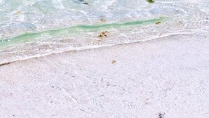 Ein Strand mit klarem, flachen Wasser und einem sandigen Ufer.