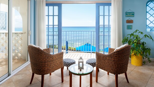 Ein Balkon mit Korbstühlen und einem Tisch, mit Blick auf das Meer.