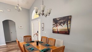 Un coin repas avec une table et des chaises en bois, un lustre et un tableau au mur.