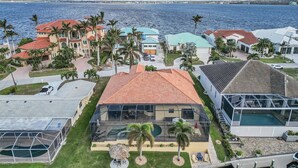 Una zona residenziale sul lungomare con case dai tetti rossi e blu, una piscina e vista sul mare.