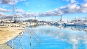 A marina with multiple yachts docked, calm water, and a distant castle-like structure. - Stunning, Upmarket and Newly furnished Apartment nearby all Major Attractions (Antibes)
