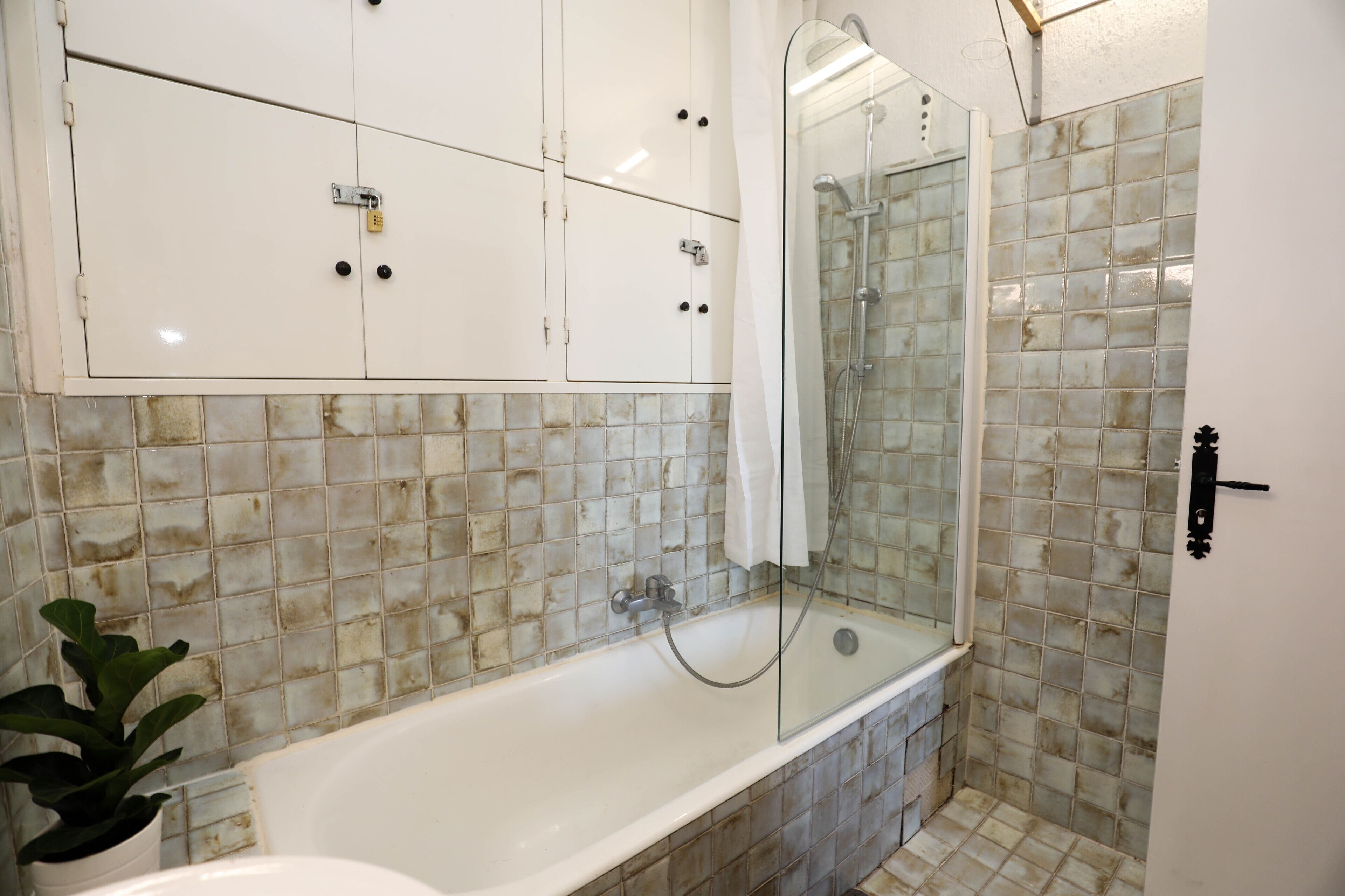 A bathroom with a bathtub, a glass-enclosed shower, and tiled walls.