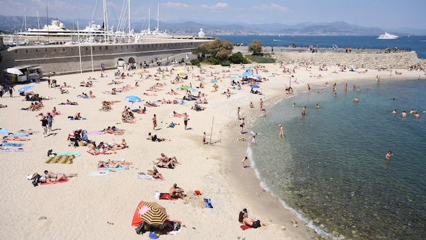A crowded beach with people sunbathing and swimming, a pier with boats, and a clear view of the sea and mountains in the background. - Stunning, Upmarket and Newly furnished Apartment nearby all Major Attractions (Antibes)