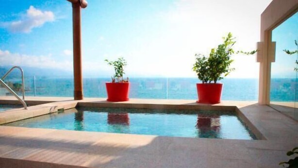 Ein Innenpool mit freiem Blick auf den Ozean, umgeben von roten Pflanzgefäßen und einem modernen architektonischen Design.