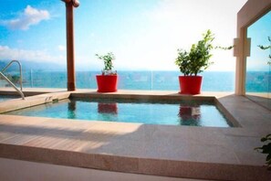 Una piscina interior amb vista clara a l'oceà, envoltada de planteres vermelles i un disseny arquitectònic modern.