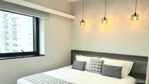 Un dormitorio con cama, ventana y tres lámparas colgantes.