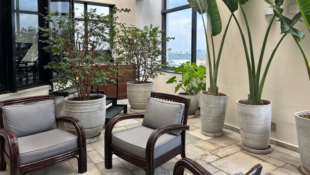 Un amplio espacio interior con ventanas grandes, plantas en macetas y asientos cómodos.