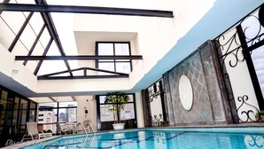 Una piscina interior con diseño moderno, incluyendo un techo de cristal y vistas a la ciudad.