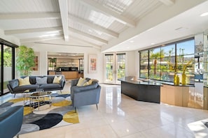 Uma sala de estar ampla com cozinha moderna, área de refeições e uma grande janela com vista para o exterior.