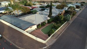 A residential area with a house featuring a large garage, a fenced yard, and a road in the foreground.