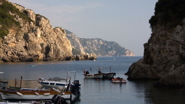 A coastal marina with boats docked, rocky cliffs, and a clear view of the sea. - Romantic sea view Studio for two (Corfu)