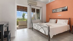 A bedroom with a bed, a desk, a chair, and a window with a view of greenery. - Romantic sea view Studio for two (Corfu)