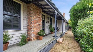 A house with a brick chimney, a porch with potted plants, and a gravel pathway. - Circa Red London Daylesford ~ Town Centre! (Daylesford)