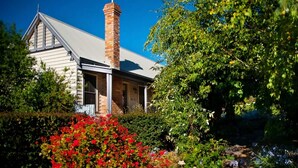 A house with a brick chimney, a porch, and a garden with red flowers. - Circa Red London Daylesford ~ Town Centre! (Daylesford)