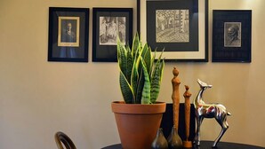 A dining table with a potted plant, wooden sculptures, and framed artwork on the wall. - Circa Red London Daylesford ~ Town Centre! (Daylesford)