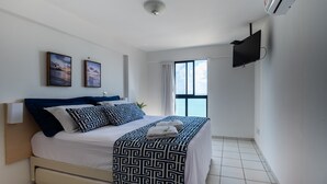A modern bedroom with a bed, two framed pictures, a flat-screen TV, and a window with curtains. - Flat with spectacular view of PONTA NEGRA BEACH, 55 MB Wi-Fi, garage (Natal)