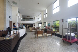 A spacious lobby with a reception desk, seating area, and large windows offering views of the outdoors. - 2-bedroom apartment with views of Morro do Careca, 250m from the sea, garage, Wi-Fi. (Natal)
