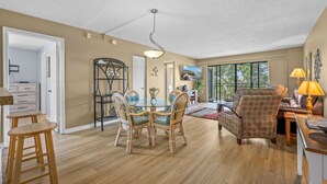 A spacious living area with a dining table, chairs, a sofa, and a TV.