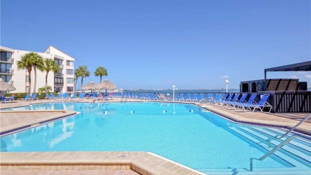 A swimming pool with blue chairs and a building in the background.