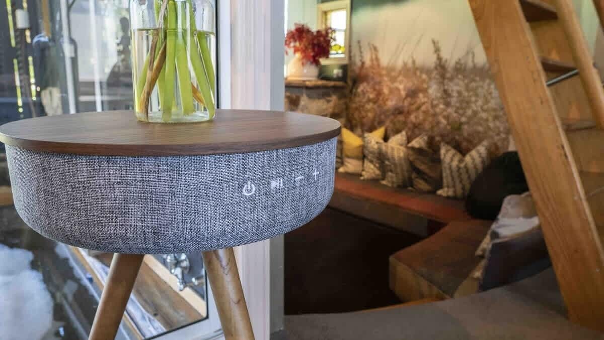 Une table ronde dotée d’un plateau en bois et d’un motif tissé, posée sur un piétement en bois.