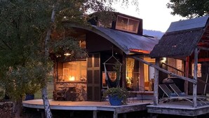 Eine rustikale Holzhütte mit Kamin, einer Holzterrasse und einem strohgedeckten Dach.