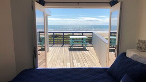 A bedroom with a view of the beach through open doors. - Ocean Front Beach House. Come and Enjoy The Sand, Sea, and Sun (Galveston)
