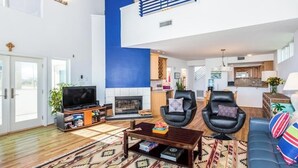 A spacious living room with a fireplace, a television, and a sofa. - Ocean Front Beach House. Come and Enjoy The Sand, Sea, and Sun (Galveston)