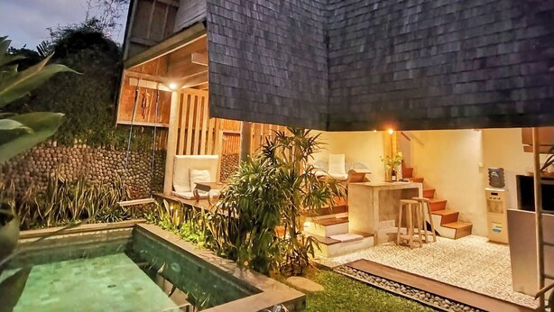 Una casa moderna con piscina, un área de estar techada al aire libre y una escalera que conduce al piso superior.