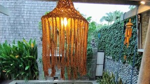 Una piscina con una lámpara colgante encima, rodeada de vegetación y un muro de piedra.