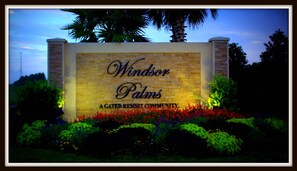 Segnaletica per Windsor Palms, una comunità turistica recintata, con un muro in pietra e fiori colorati di fronte.