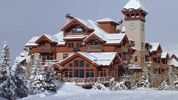 A large, multi-story lodge with a prominent clock tower, surrounded by snow-covered trees and a clear sky. - True Ski in Ski Out Located In Arrowhead village. 3 Bed / 3 Bath Unit (Edwards)