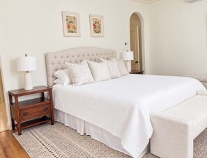 A bedroom with a large bed, a nightstand with drawers, two wall-mounted lamps, and a patterned rug. - True Ski in Ski Out Located In Arrowhead village. 3 Bed / 3 Bath Unit (Edwards)