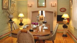 Ein Esszimmer mit Holztisch, Korbstühlen und einem Kamin.