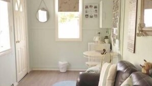 Ein Wohnzimmer mit einem braunen Ledersofa, zwei runden Teppichen, einem weißen Schrank und einem Fenster mit Blick.