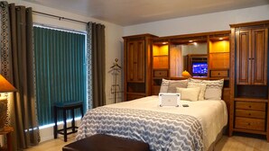 Une chambre à coucher avec un grand lit, une armoire en bois, un bureau et une chaise.