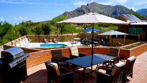 Une terrasse extérieure dotée d’une piscine, d’un barbecue et d’un espace détente agrémenté de parasols.