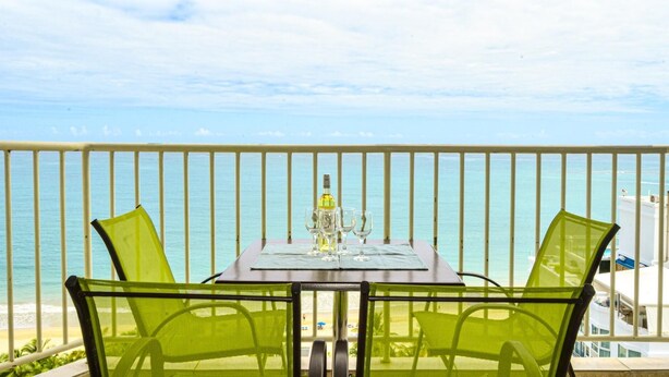 Ein Balkon mit Tisch für zwei Personen mit Blick auf einen Strand.