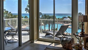 A balcony with a view of the ocean, a pool, and lounge chairs. - Gulf Front**Free Beach Service & Wi-Fi**  (Miramar Beach)