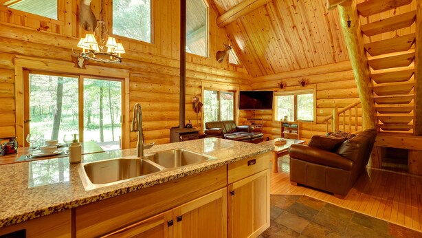 A log cabin interior with a kitchen, dining area, and living room. - Secluded Log Cabin in NW Michigan: Hot Tub & Deck (Hersey)