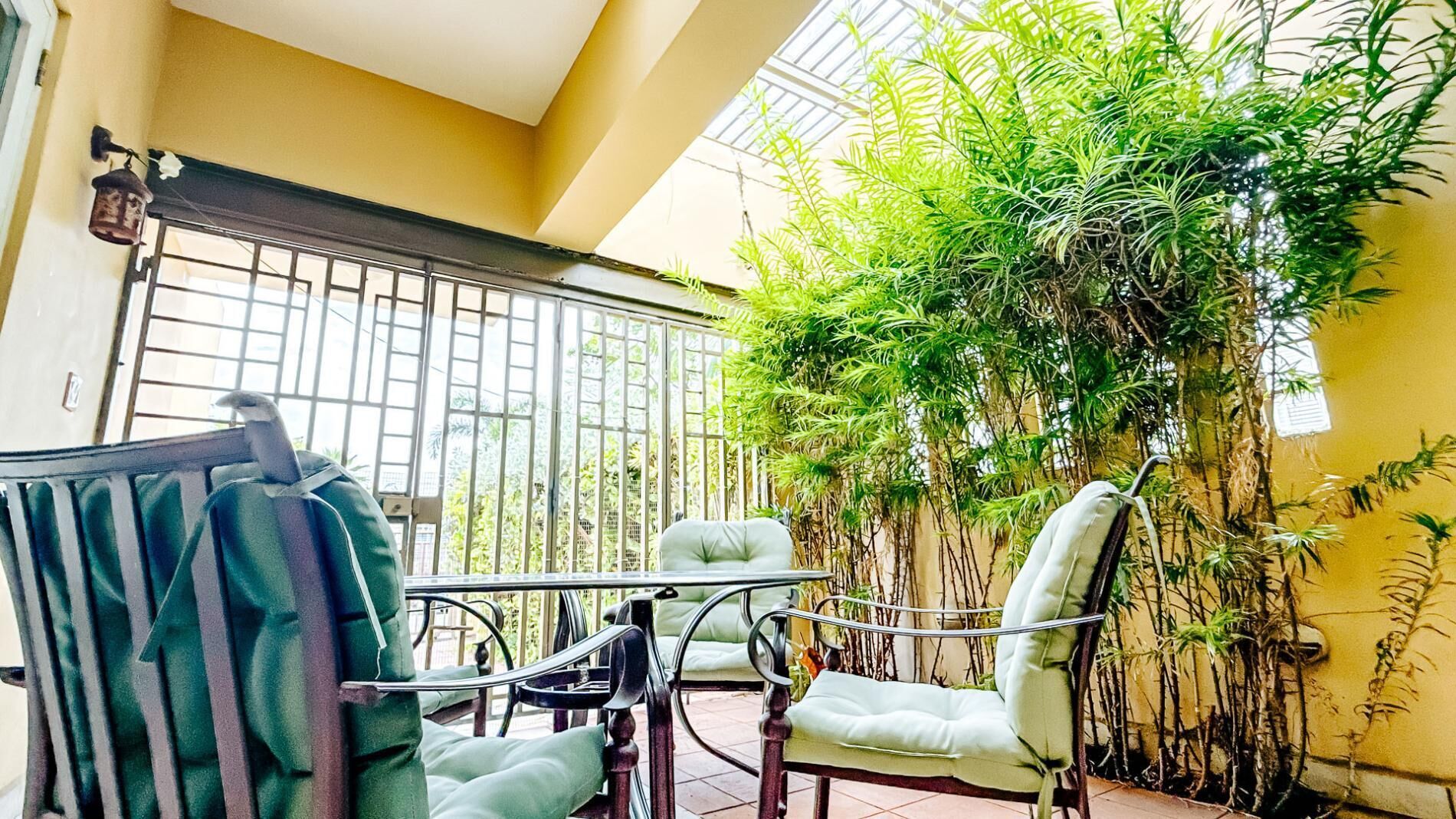 A balcony with a metal railing, a table, two chairs, and a hanging plant.