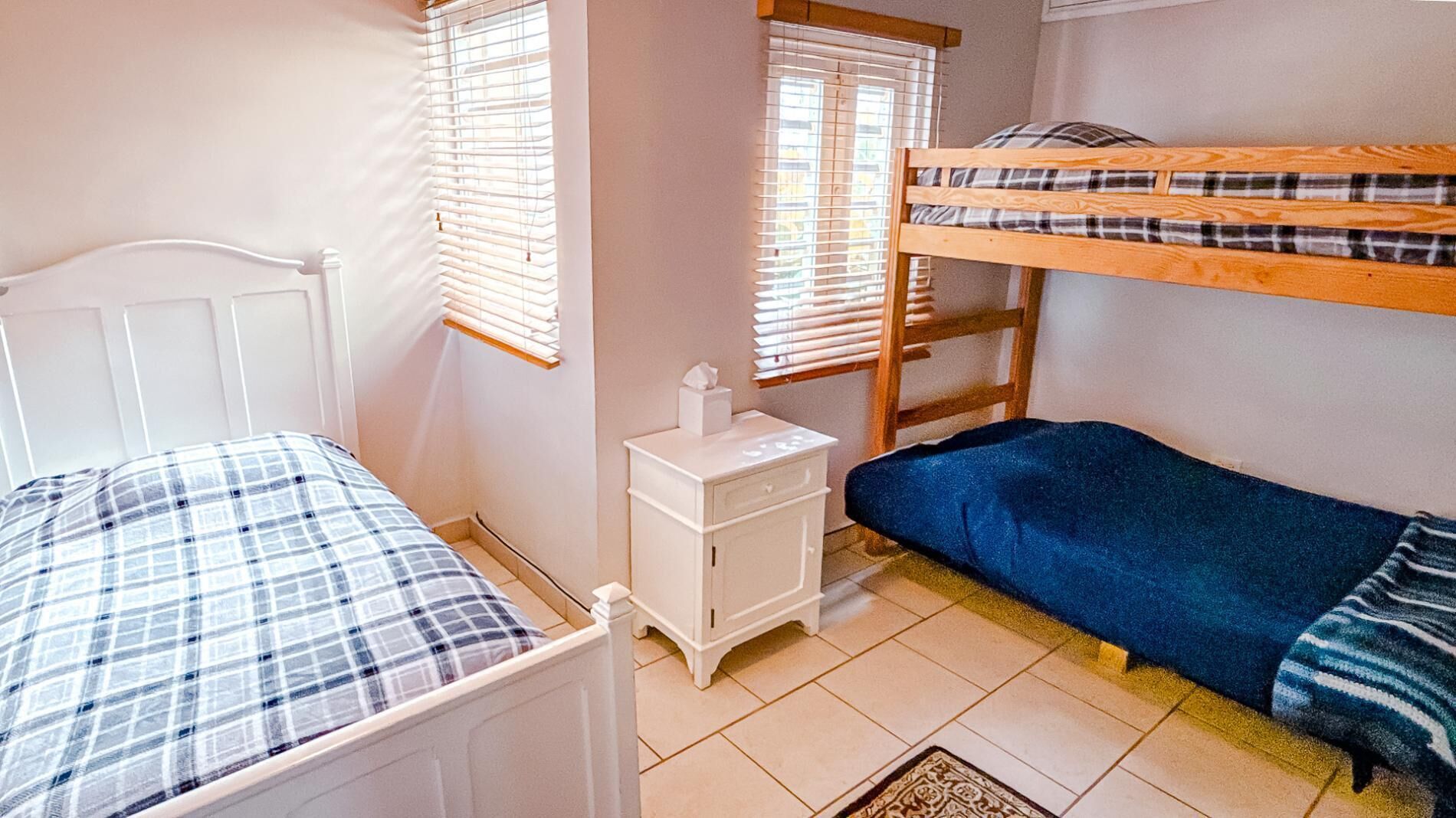 Un dormitorio con dos literas, una mesita de noche y una ventana con persianas.