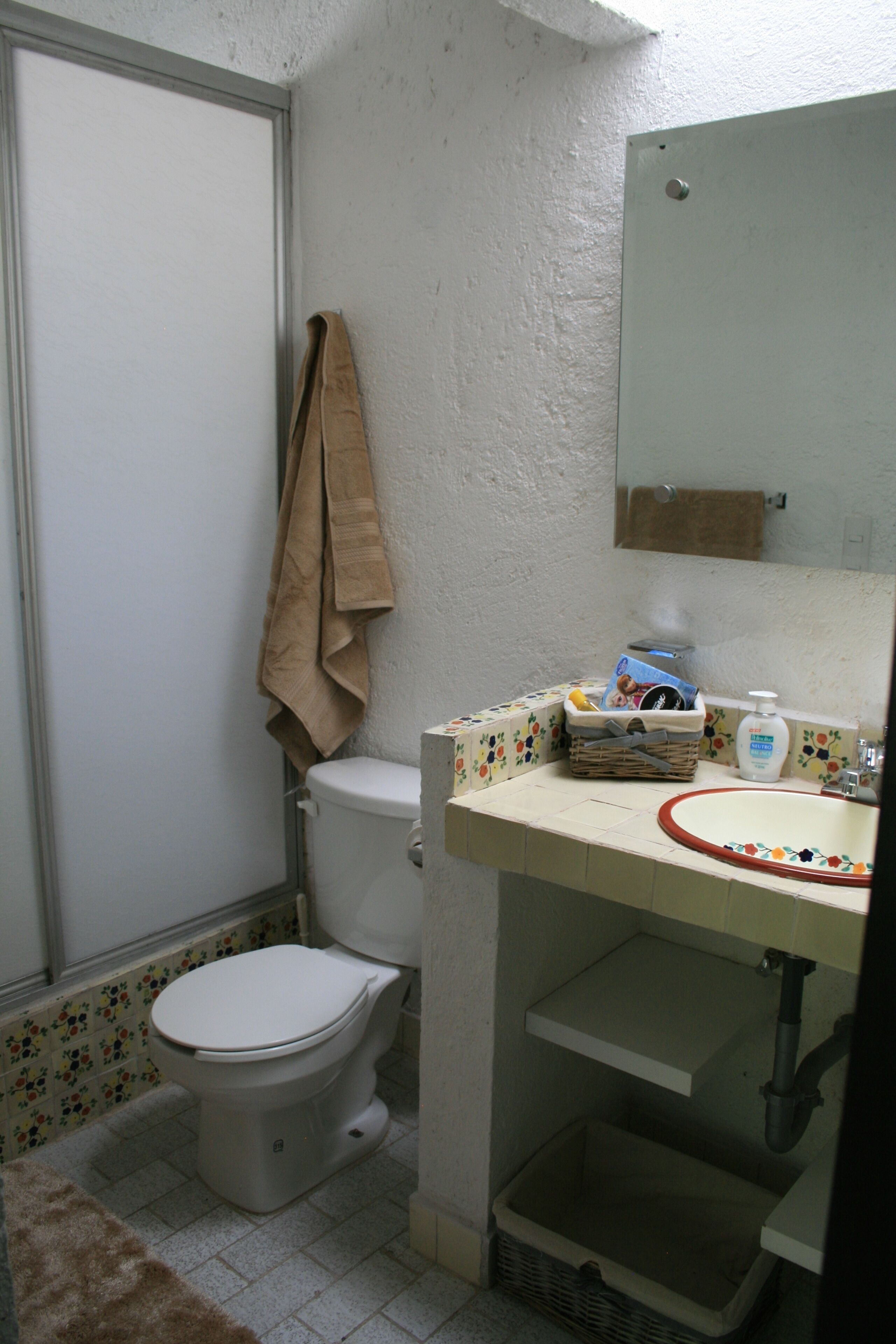 Un baño pequeño con inodoro, lavamanos y espejo.