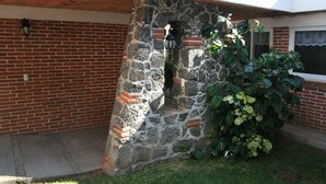 A stone archway leading to a brick building with a window and a plant in the foreground.