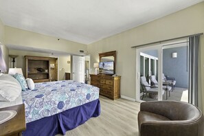 Une chambre d’hôtel comprenant un lit, une commode, une télévision et un balcon avec des sièges.
