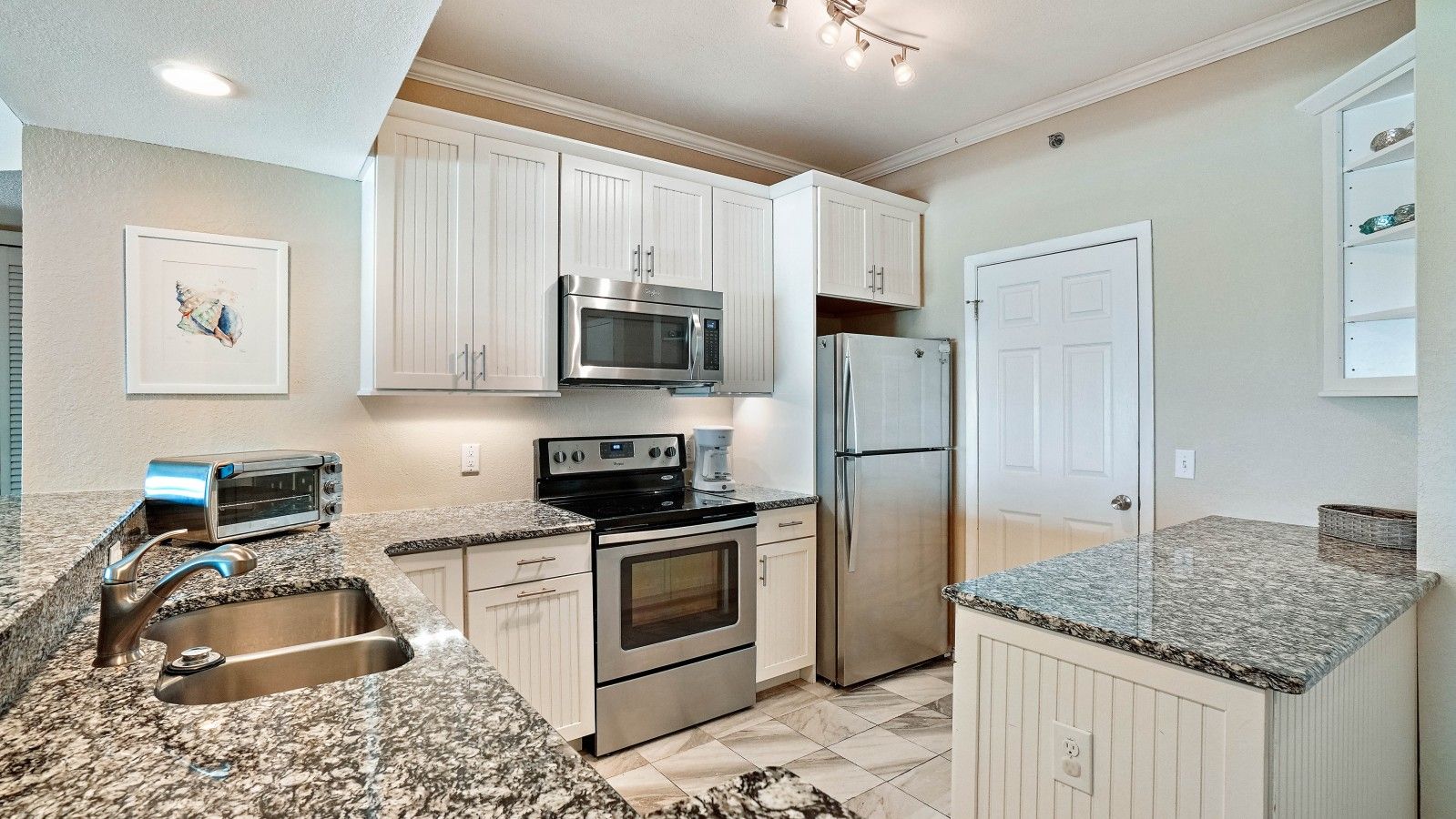 A kitchen with white cabinets, stainless steel appliances, granite countertops, and a built-in oven.