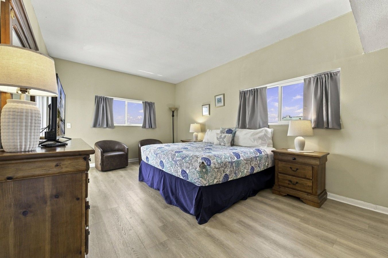 Une chambre à coucher comprenant un lit, deux chaises, une commode, une table de chevet et une lampe.